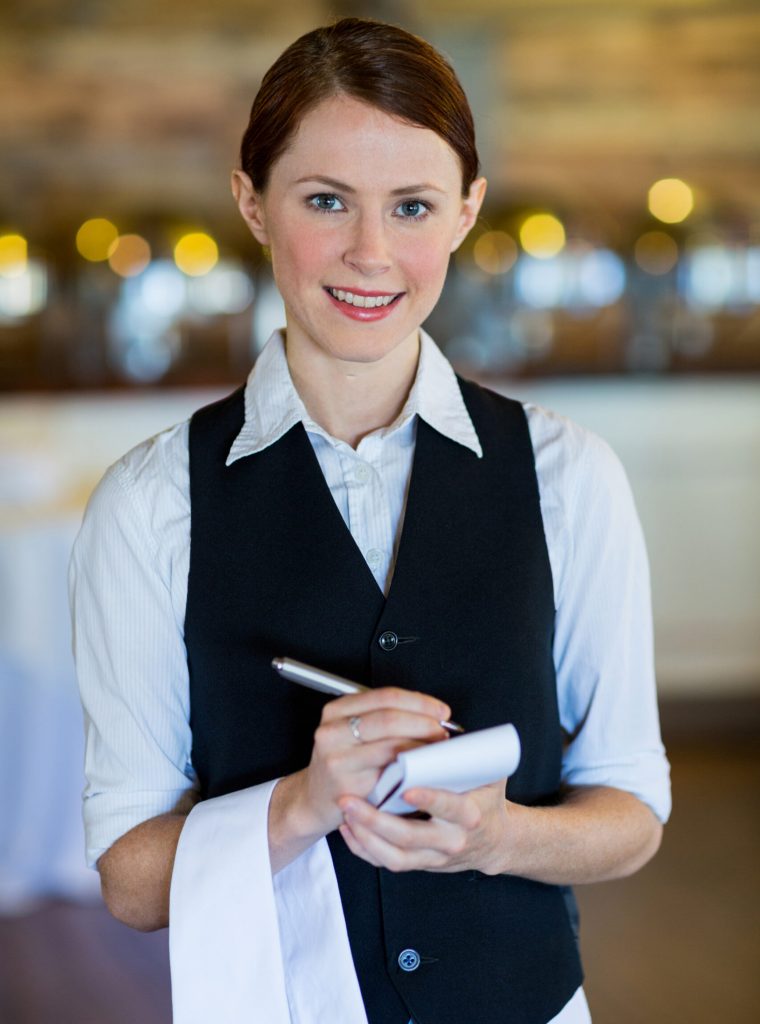 Portrait of smiling waitress taking order in restaurant